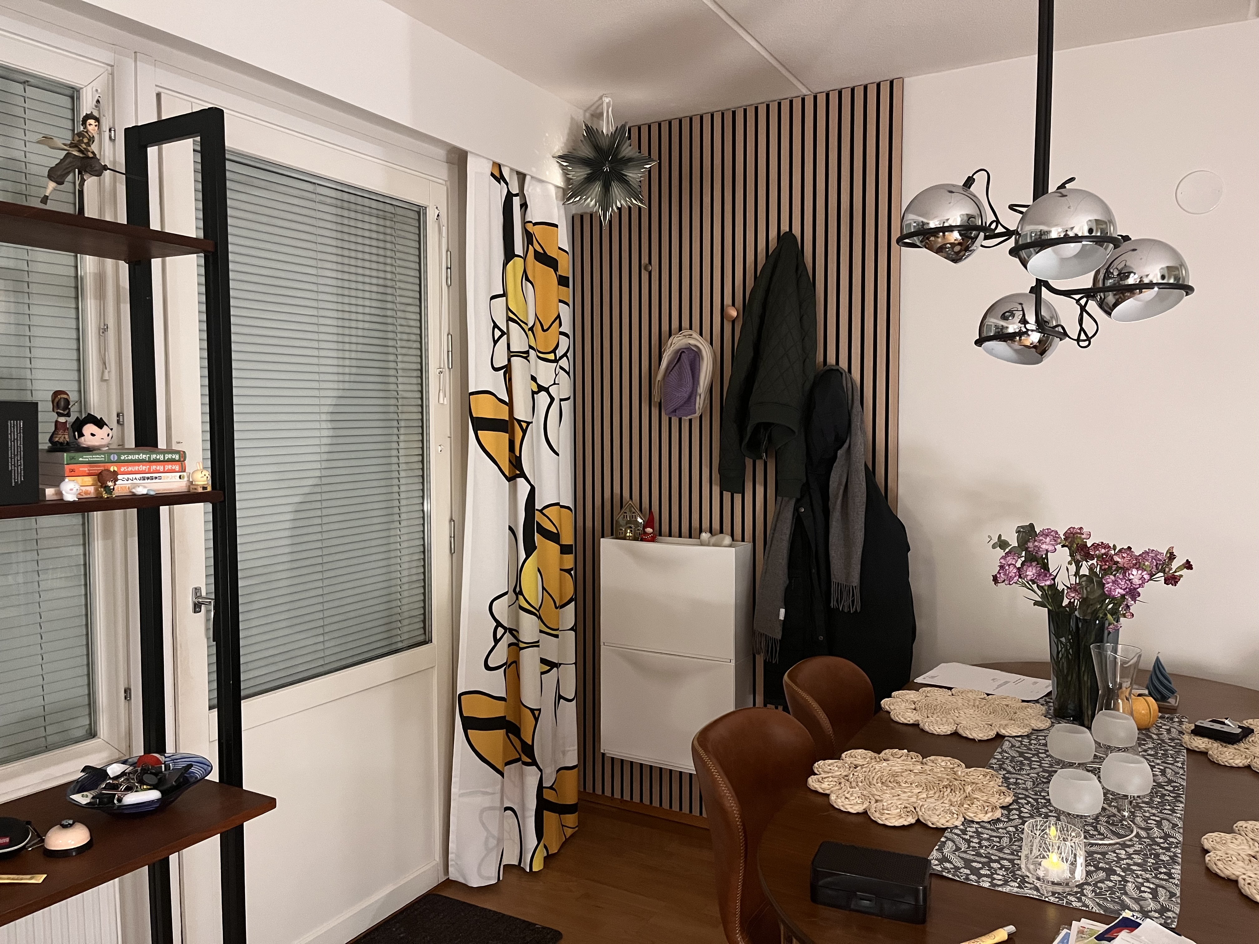 An installed wood paneling with some coats hanging off of colored knobs